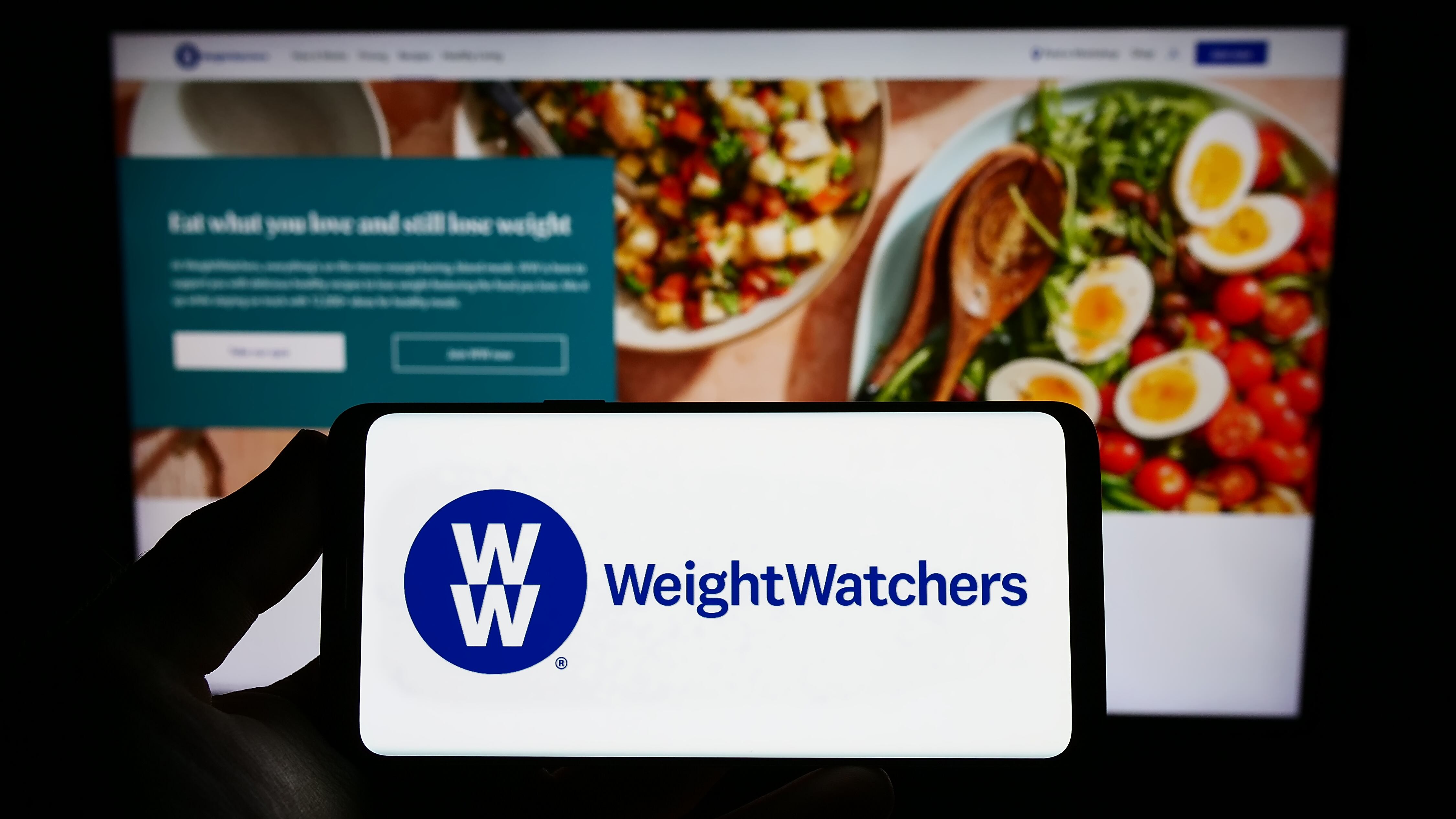 The WeightWatchers log appears on a cellphone in front of a computer screen.